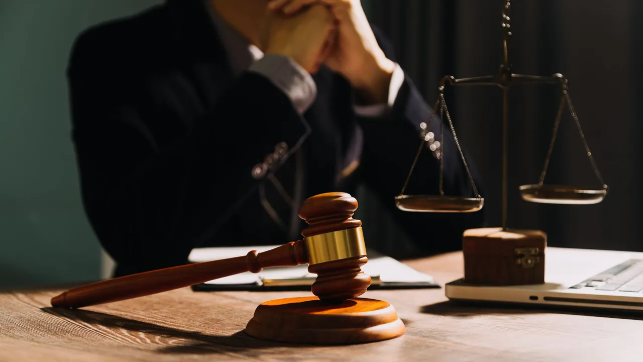 Attorney at a desk behind a gavel and scales of justice