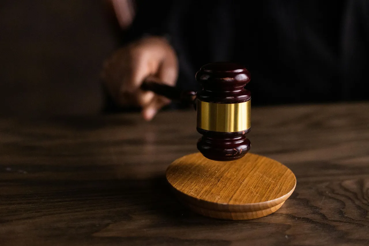 Hand holding a wooden gavel above its sound block