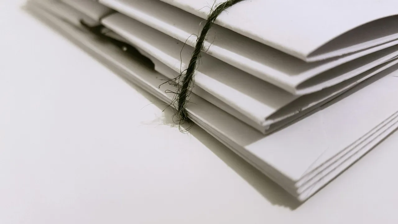 Stack of white document folders tied with twine