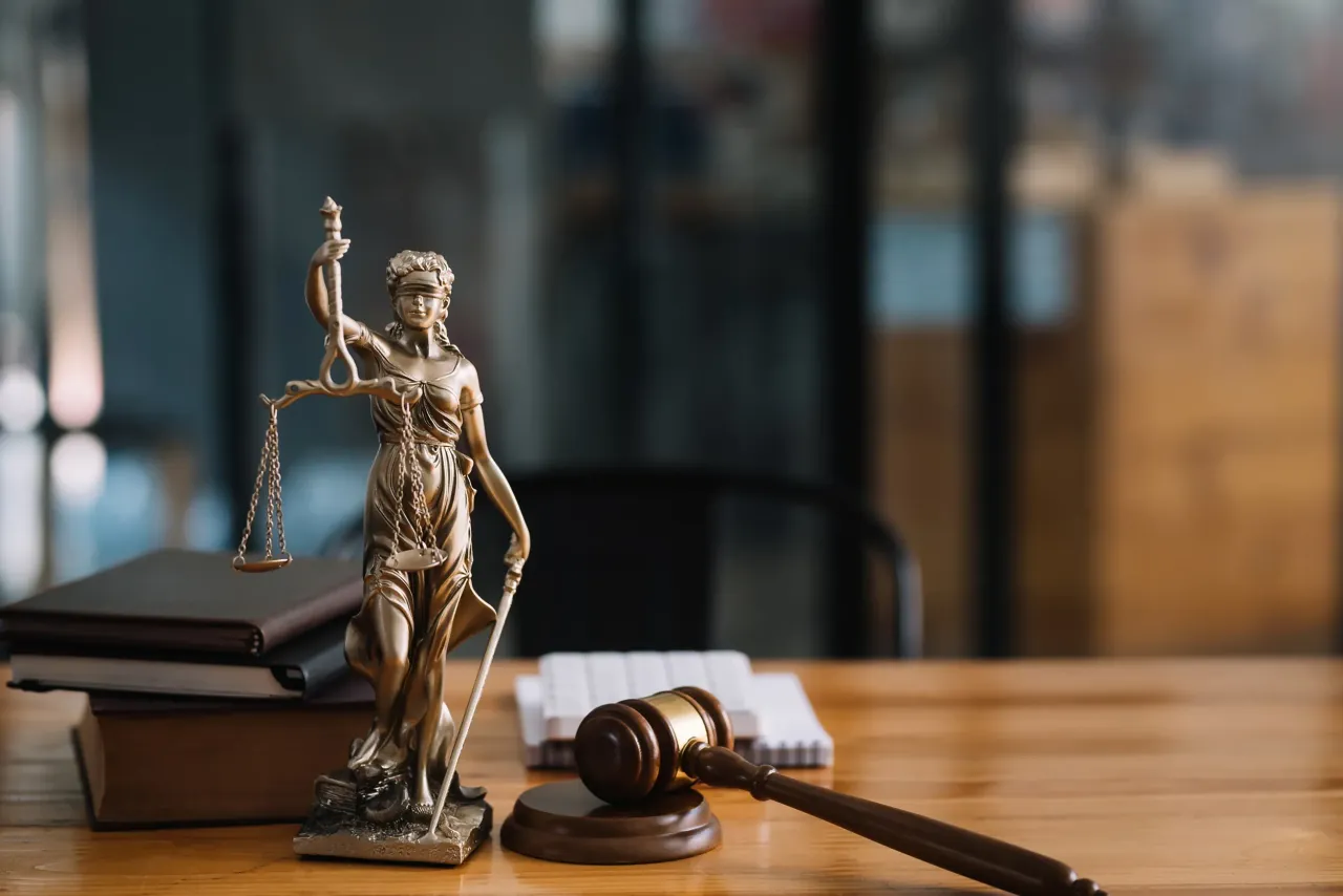 Statue of Lady Justice beside a gavel on a desk