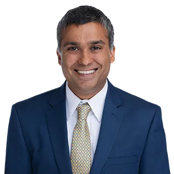 Attorney Jay Mukerji in a navy suit and gold tie